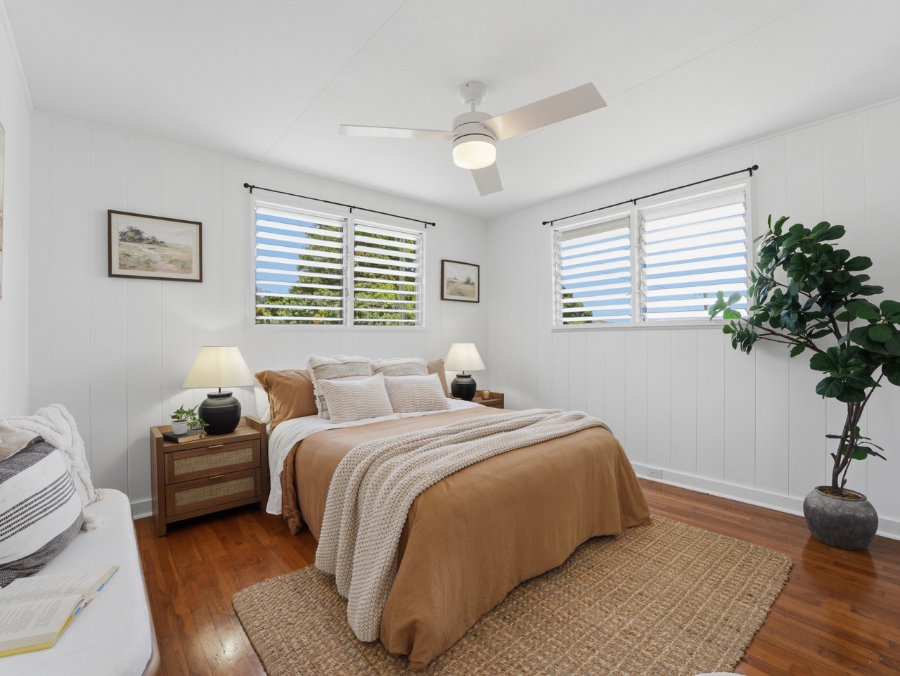 Primary bedroom with king bed, hardwood floors and louvered windows
