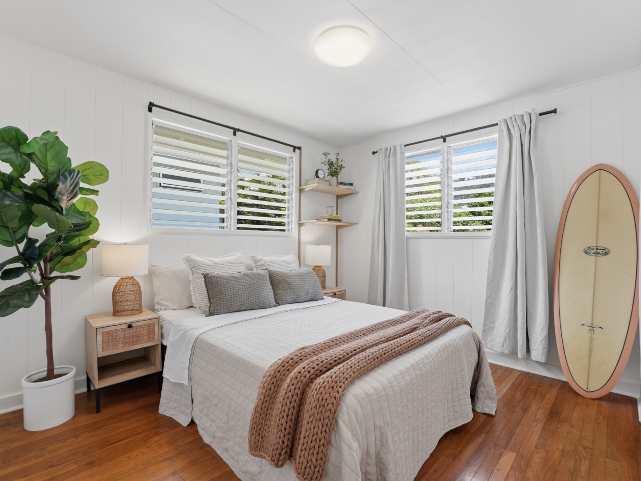 Bedroom with surfboard, soft linens and natural light