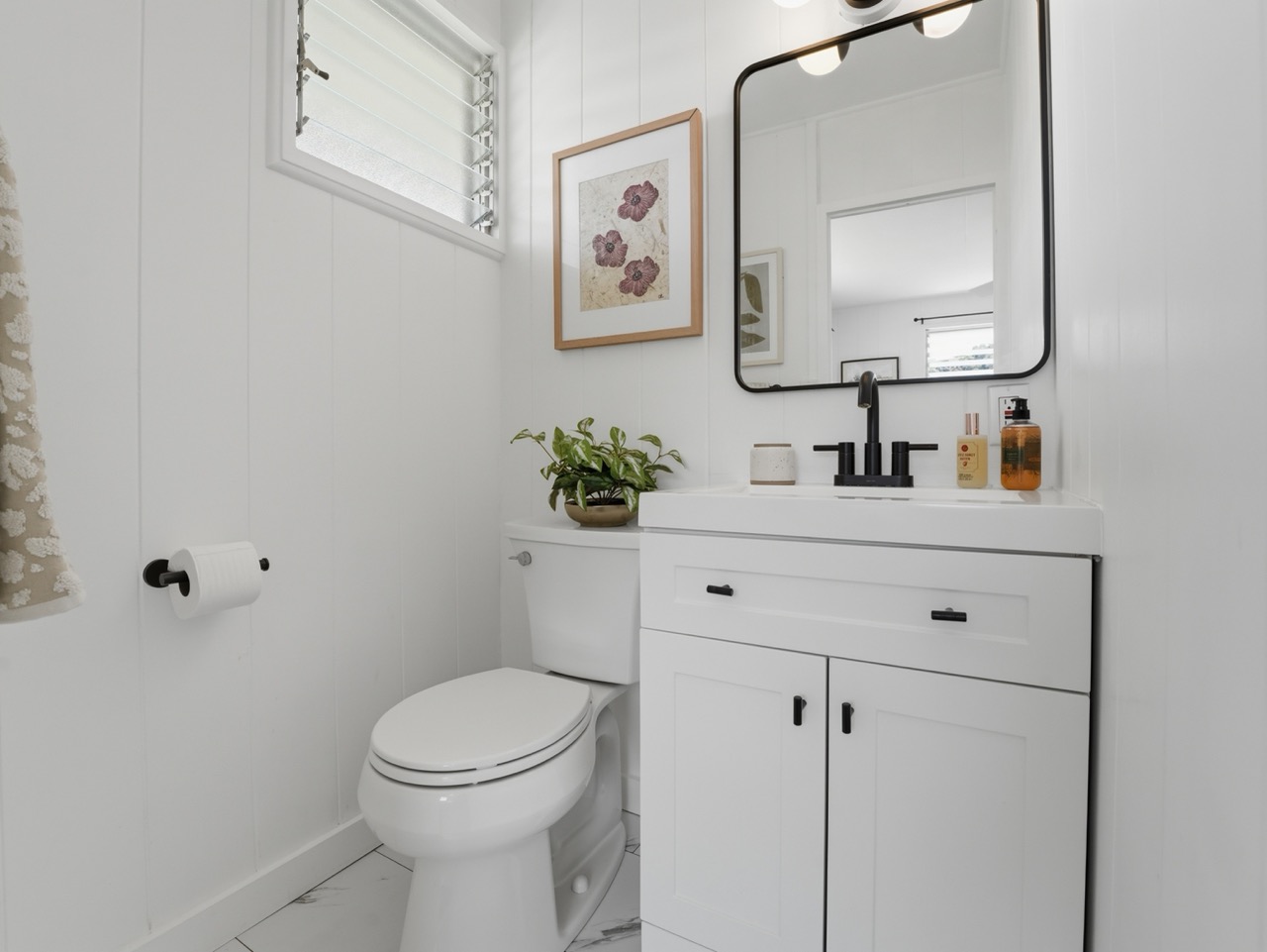 Half bath with white vanity and framed art