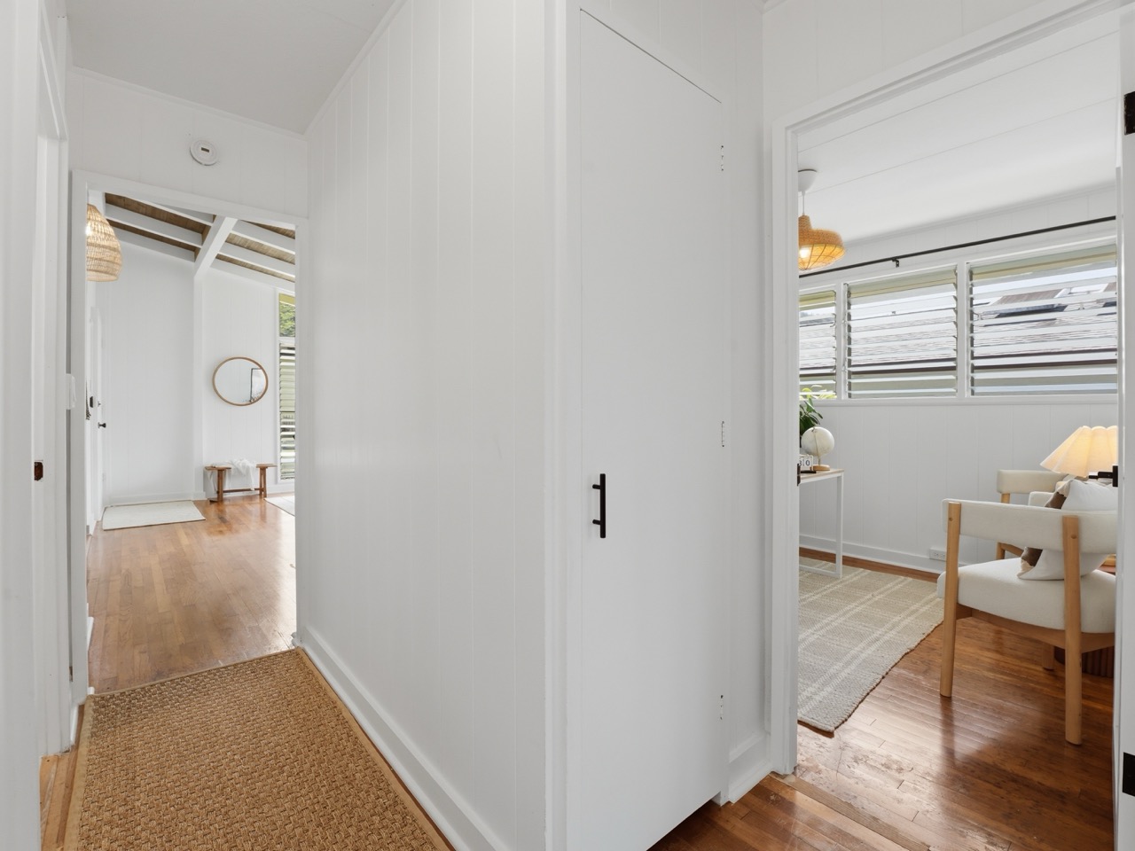 Hardwood hallway connecting bedrooms and office