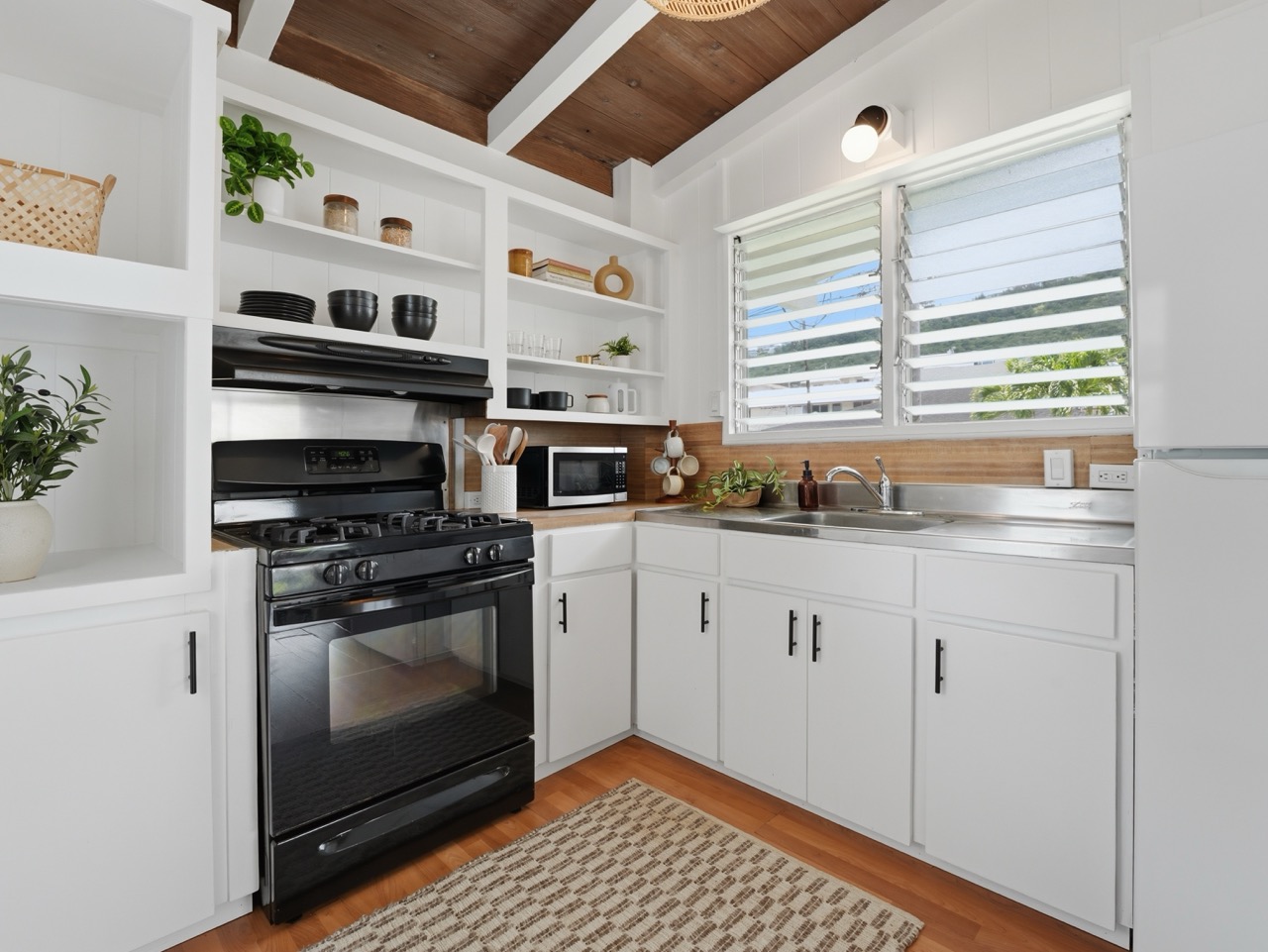 White kitchen with gas range, open shelving and louvered window