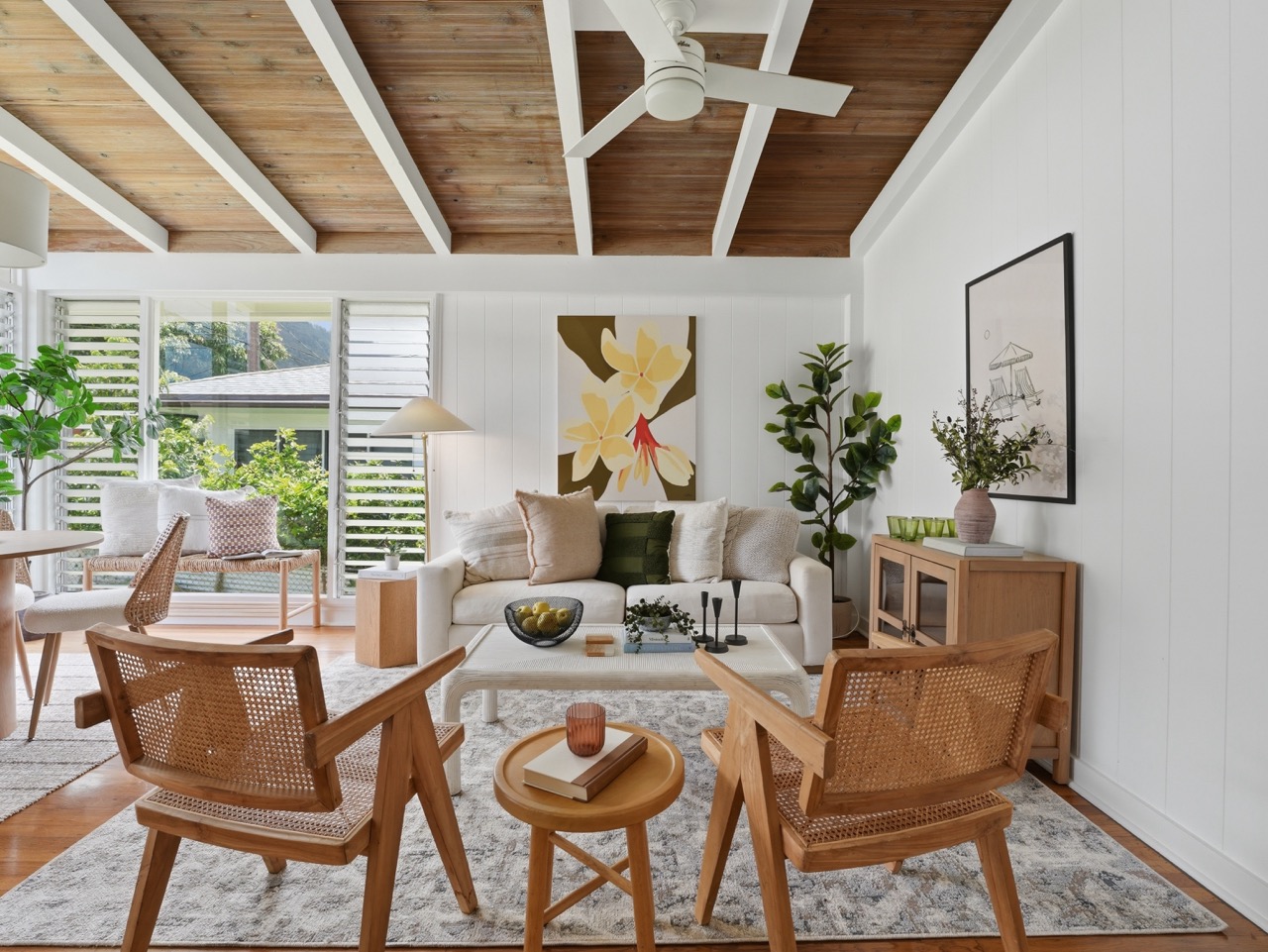 Living room with cane chairs facing the sofa and floral art